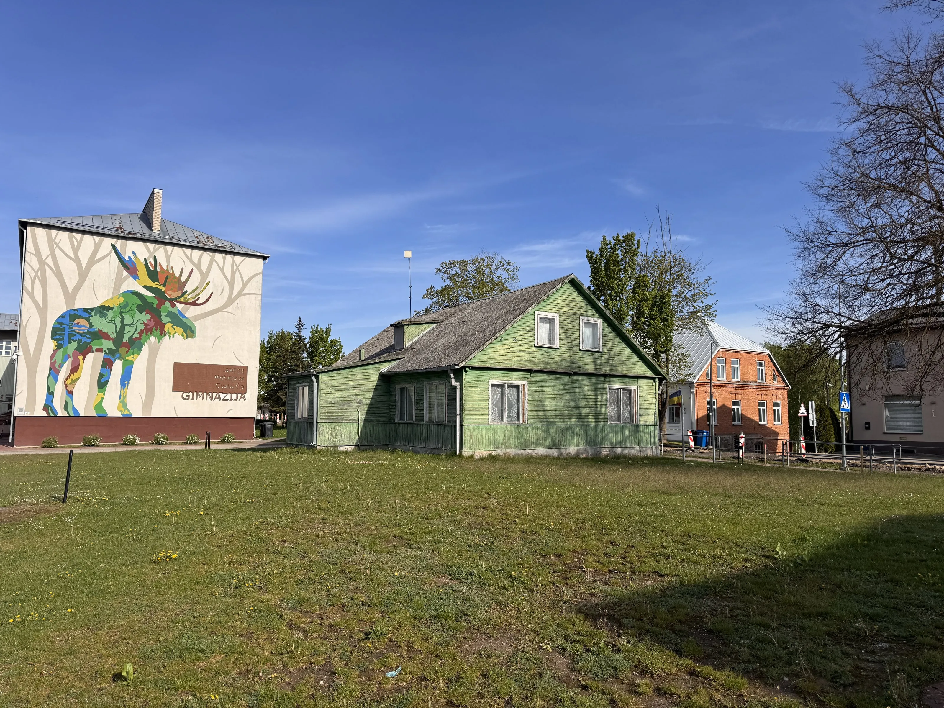 The green timber house in Lazdijai, the town's moose mural behind it